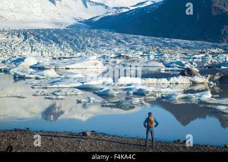 Persona accanto a Fjallsarlon laguna iceberg, al di sotto del ghiacciaio Fjallsjokull. Vatnajokull National Park, Sudhurland, Islanda. Foto Stock