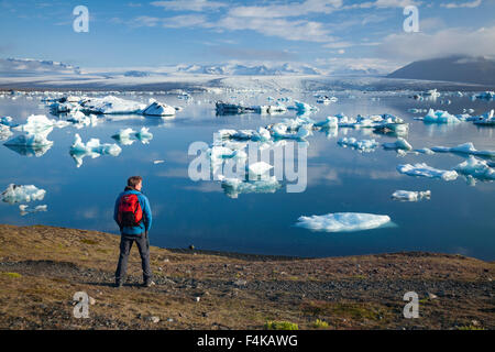 Escursionista sulla riva di Jokulsarlon laguna iceberg, Vatnajokull National Park, Sudhurland, Islanda. Foto Stock