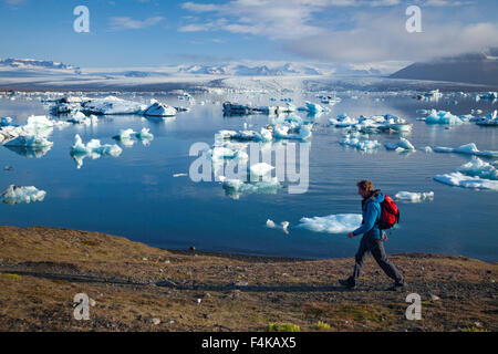 Escursionista sulla riva di Jokulsarlon laguna iceberg, Vatnajokull National Park, Sudhurland, Islanda. Foto Stock