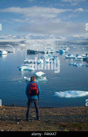 Escursionista sulla riva di Jokulsarlon laguna iceberg, Vatnajokull National Park, Sudhurland, Islanda. Foto Stock