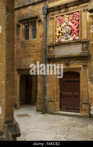 Un piccolo cortile appartato in Sherborne School. Al di sopra di una porta è lo stemma reale di re Edward 6th. Il Dorset, Inghilterra, Regno Unito. Foto Stock