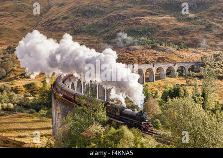 Il Giacobita treno a vapore che insuffla vapore dallo scarico come si attraversa il viadotto Glenfinnan, Highland, Scotland, Regno Unito. Foto Stock