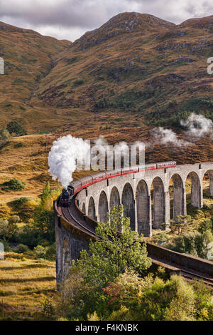 Il Giacobita treno a vapore che insuffla vapore dallo scarico come si attraversa il viadotto Glenfinnan, Highland, Scotland, Regno Unito. Foto Stock