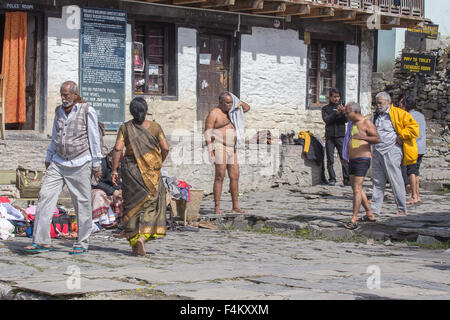 Pellegrini che prendono la doccia sotto i 108 rubinetti sacri al Tempio di Muktinath, Nepal. Foto Stock