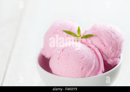 Palline di gelato alla fragola in ciotola di legno rustico vintage sfondo tabella. Foto Stock