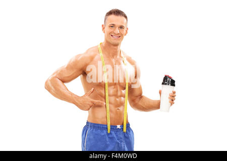 Giovane atleta maschio tenendo una bottiglia con protein shake e rivolti verso di essa con la sua mano isolati su sfondo bianco Foto Stock