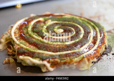 Giapponese Okonomiyaki sulla piastra calda Foto Stock