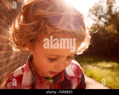 Ritratto di capelli ricci toddler boy in un controllato shirt all'aperto Foto Stock