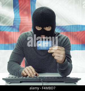 Di carnagione scura hacker con la carta di credito in mano e bandiera su sfondo - Isole Faerøer Foto Stock