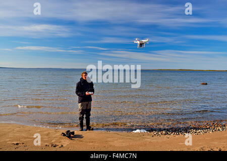 Giovane uomo drone operativo elicottero sulla riva del lago Ennadi, Arctic Haven Lodge, Nunavut, Canada Foto Stock