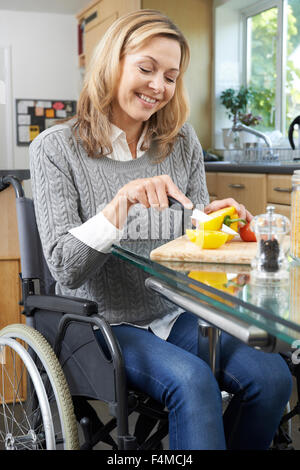 Donna disabile in sedia a rotelle la preparazione di pasto in cucina Foto Stock
