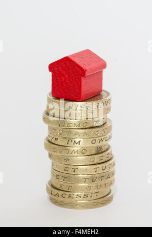 Pila di British una libbra di monete con un monopolio di legno-casa in stile seduti sulla parte superiore Foto Stock