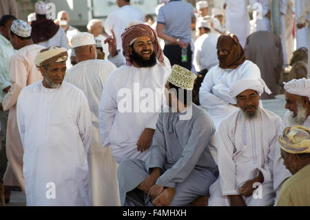 Omani uomini sorridenti e ridere guardando il bestiame per la vendita presso il Nizwah giovedì giorno di mercato. Foto Stock