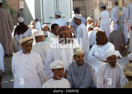 Omani uomini sorridenti e ridere guardando il bestiame per la vendita presso il Nizwah giovedì giorno di mercato. Foto Stock