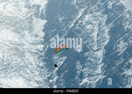Para pilota di parapendio volare alto nella valle di Chamonix con il ghiaccio del ghiacciaio dei Bossons glacier dietro Foto Stock