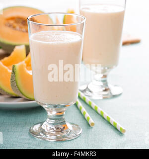 Un sano frullato di melone in un bicchiere alto con melone freschi Foto Stock