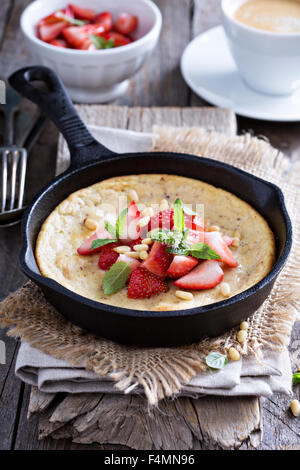 Pancake cotti al forno in ghisa padella con fragole fresche e pinoli Foto Stock