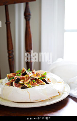 Pavlova cake con fichi freschi, il cioccolato bianco e crema di ricotta e scorza di arancia Foto Stock