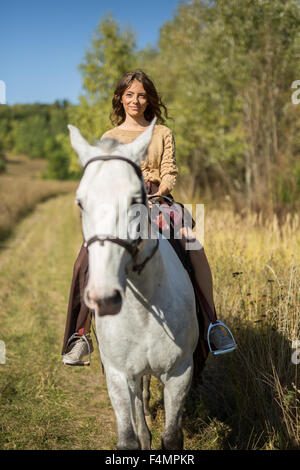 Bella ragazza in sella ad un cavallo bianco Foto Stock