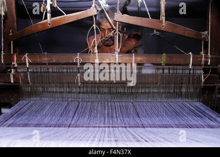 Vecchio uomo tessendo telaio mano indiano in un vecchio tradizionale macchina di tessitura di legno Foto Stock