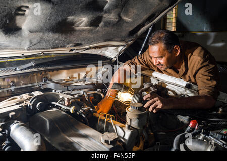 Un meccanico di automobili è la riparazione di un tedesco BMW auto in un garage convenzionato situato nel sobborgo di fort Foto Stock