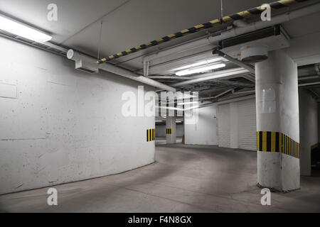 Svuotare il parcheggio sotterraneo interno, pareti di cemento e colonne Foto Stock