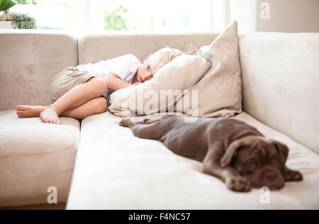 Triste ragazzino sdraiato sul divano in soggiorno Foto Stock
