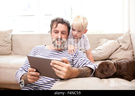 L uomo e il suo piccolo figlio di relax con tavoletta digitale nel soggiorno Foto Stock