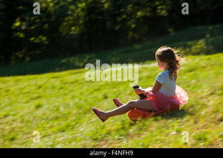 Bambina la guida di Bob in discesa su un prato Foto Stock