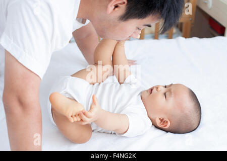 Cinesi padre e figlio giocando a letto, persone reali Foto Stock