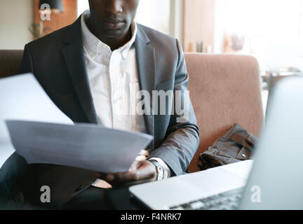 Ritagliato shot del giovane imprenditore andando attraverso alcune pratiche. African business executive la lettura di documenti mentre si è seduti alla co Foto Stock