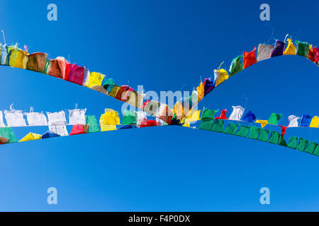 Tibetean colorati bandiere di preghiera sono sventolare di fronte blu cielo Foto Stock