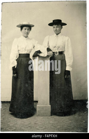 Ritratto di due donne adulte in cappelli e abiti lunghi appoggiata sul pilastro, circa 1870 Foto Stock