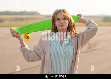 Bella ragazza in piedi con uno skateboard in strada. Foto Stock