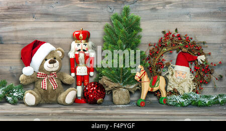Nostalgico decorazione di Natale. Giocattoli antichi Orsacchiotto a Santa Claus Red Hat e schiaccianoci. Foto Stock