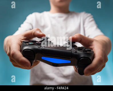 Un bambino che gioca giochi per computer con una PS4 Playstation 4 controller Foto Stock