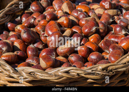 Cesto in Vimini pieno di dolci di castagne organico per la vendita in un mercato di paese Foto Stock