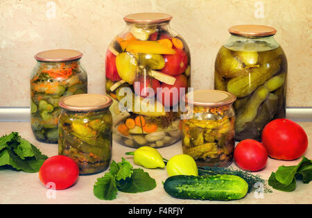 Home canning: vasi con le conserve di lungo con carote e spezie cetrioli , ermeticamente coperchi in metallo. Nelle vicinanze si trovano i pomodori freschi, Foto Stock