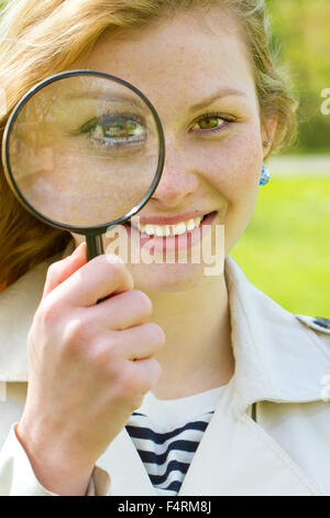 Giovane donna con lente di ingrandimento Foto Stock