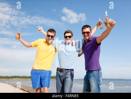 Happy amici con bottiglie di birra sulla spiaggia Foto Stock