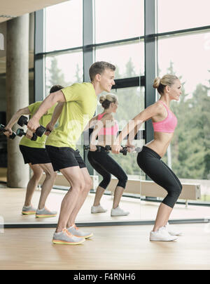 Uomo sorridente e la donna con manubri in palestra Foto Stock