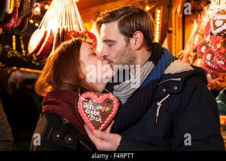 Giovane kissing sul mercato di Natale tedesco con pan di zenzero cuore Foto Stock