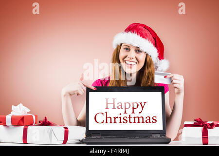 Immagine composita di festosa redhead shopping online con il computer portatile Foto Stock