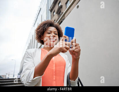 Felice donna africana con lo smartphone in città Foto Stock