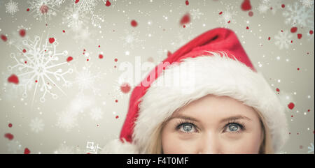 Immagine composita di festosa bionda cercando fino a santa hat Foto Stock