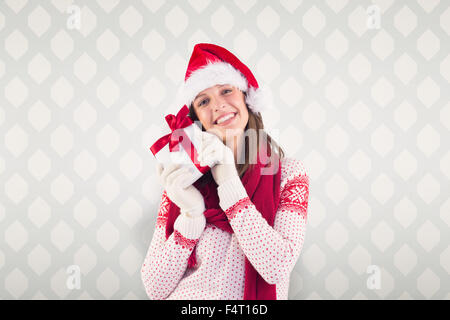 Immagine composita della donna attraente indossando santa hat con dono Foto Stock