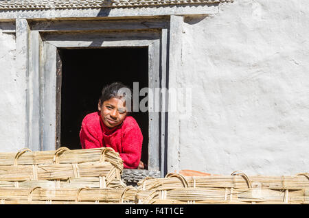 Bambino in un maglione rosso guardando fuori di una finestra di agricoltori bianchi house Foto Stock