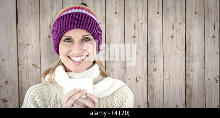 Immagine composita di incandescente donna che indossa un maglione bianco e un colorato hat contro backgrou bianco Foto Stock
