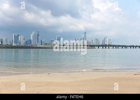 Spiaggia di sabbia in primo piano con la nuova autostrada sulla baia e la città di Panama grattacieli in background, Panama, America Centrale Foto Stock