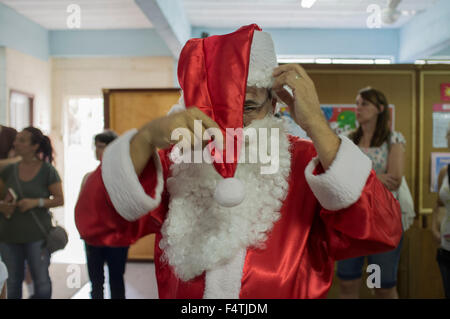 Uomo abiti fino a Santa Claus per visitare quartieri poveri e distribuire doni per i bambini a Natale. Nova Friburgo Città, Stato di Rio de Janeiro, Brasile. Foto Stock